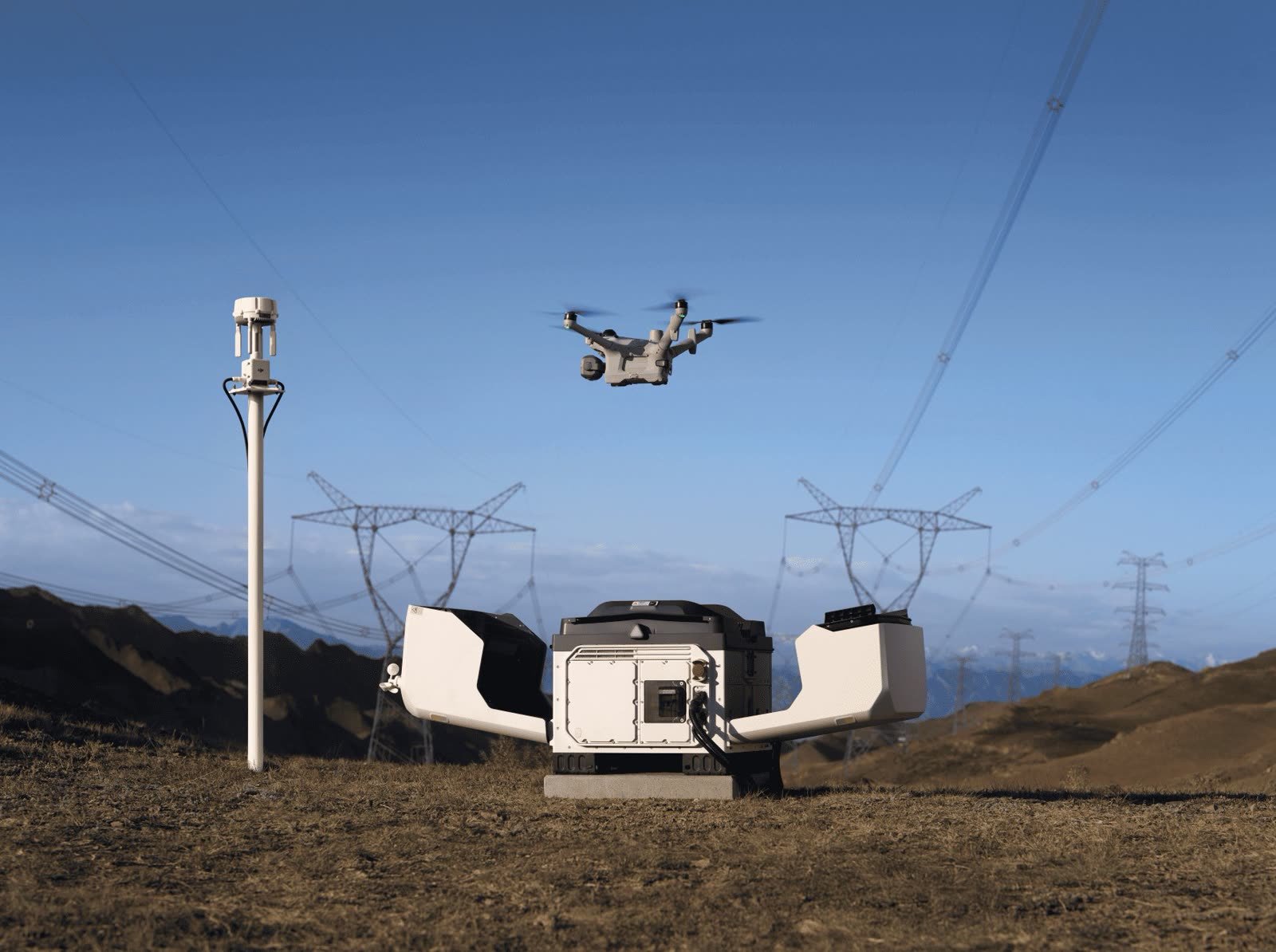 Le DJI Dock 4 ouvert en montagne, le Matrice 5TD en vol devant des pylônes haute tension